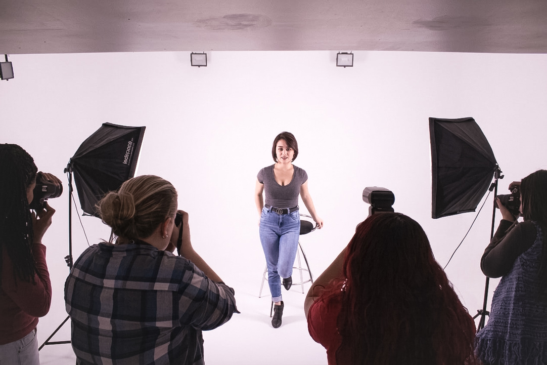 Alunos fotografando modelo em aula prática de estúdio